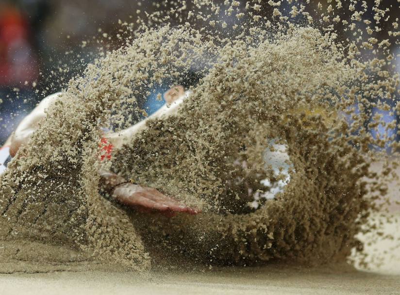 Mondiali di atletica a Pechino. Lo scatto  a effetto. Dietro la sabbia il cinese Wang Jianan (Reuters)